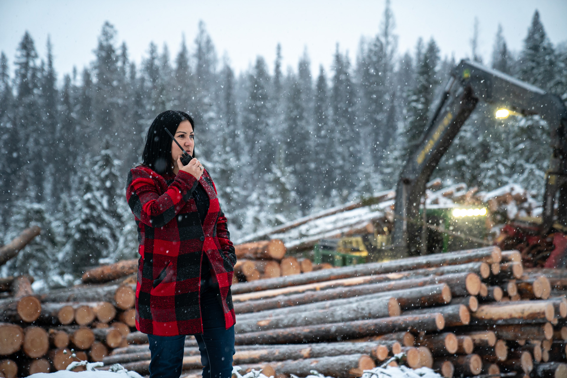 woman in plaid coat talking in a walkie talkie among cut trees by Bruno Florin for BDC Beyond Business with Cossette