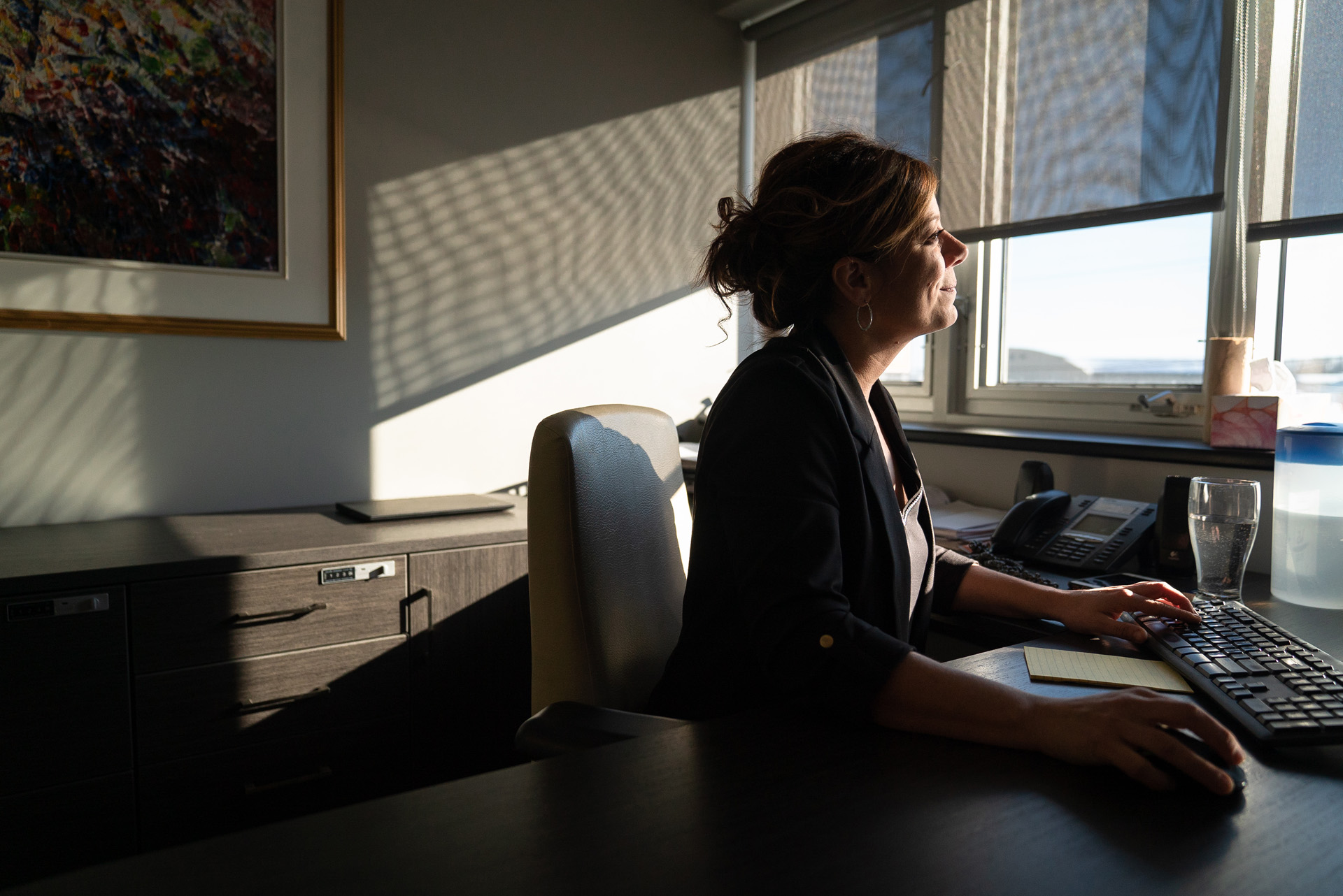 woman working in office looking at computer face in the sun smiling by Bruno Florin for BDC Beyond Business with Cossette