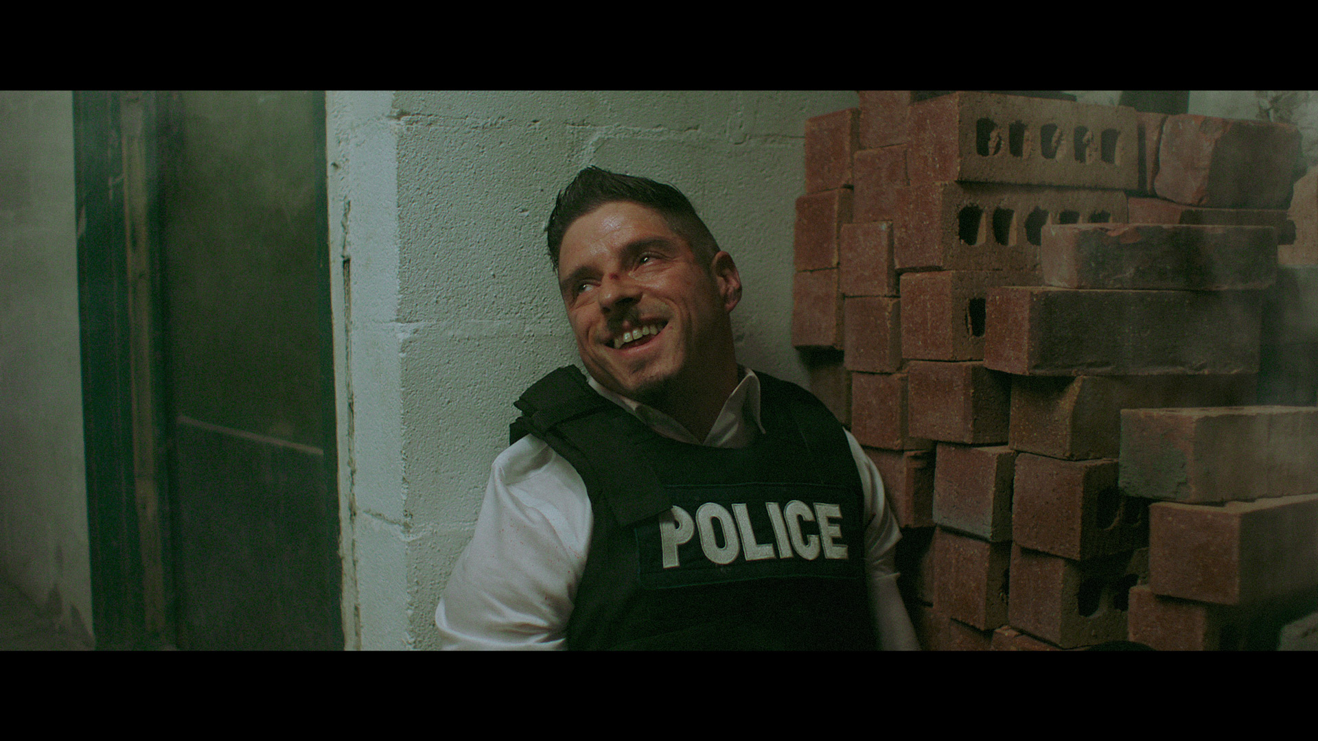 actors Hugolin Chevrette-Landesque posing as cop brassed against a wall looking delirious for TV series La Loi C'est La Loi filmed by Les Gamins for TV5 Unis