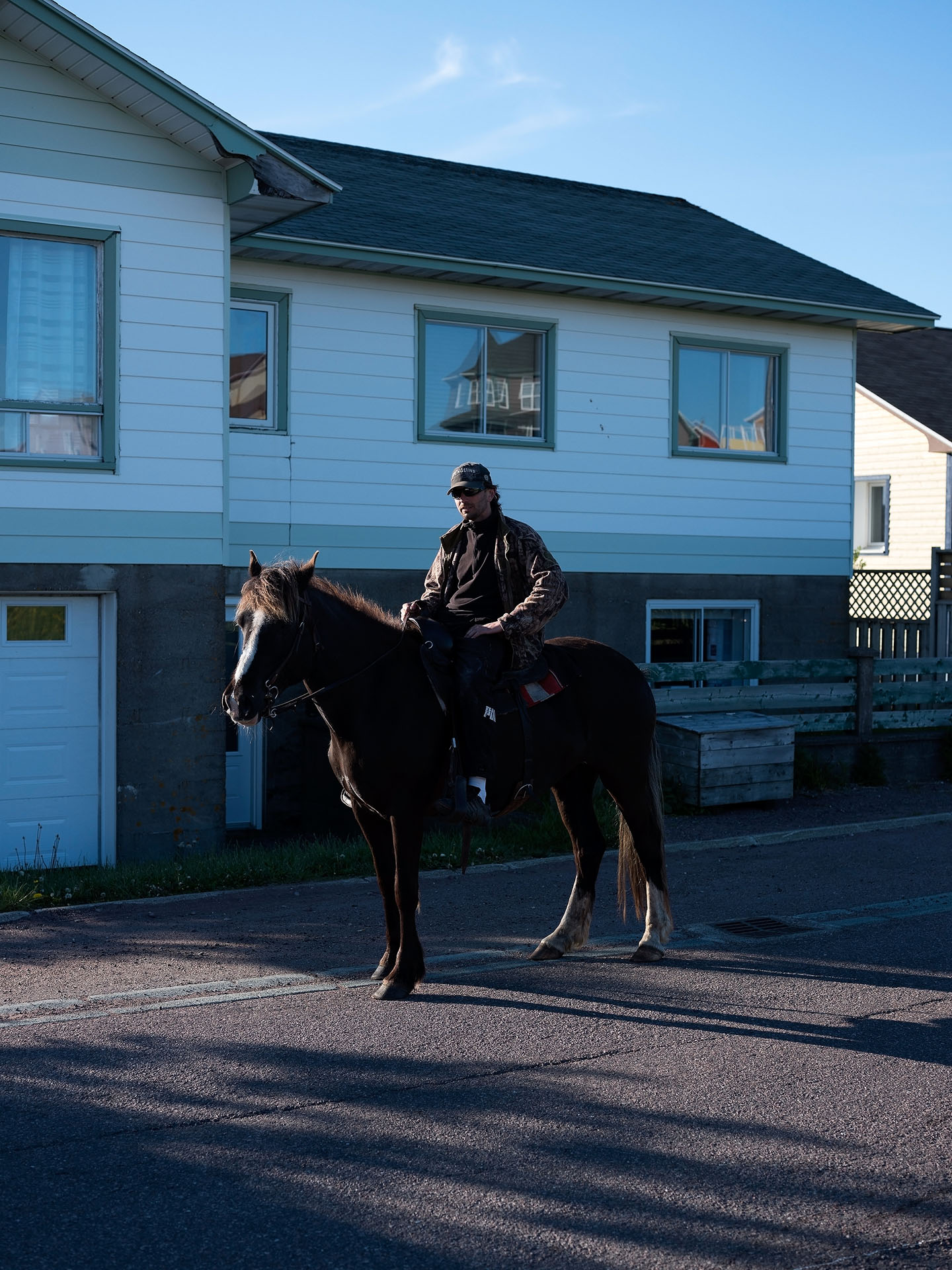 man horseback riding in the street wearing sunglasses by Guillaume Simoneau in Saint-Pierre-et-Miquelon for M le mag Le Monde