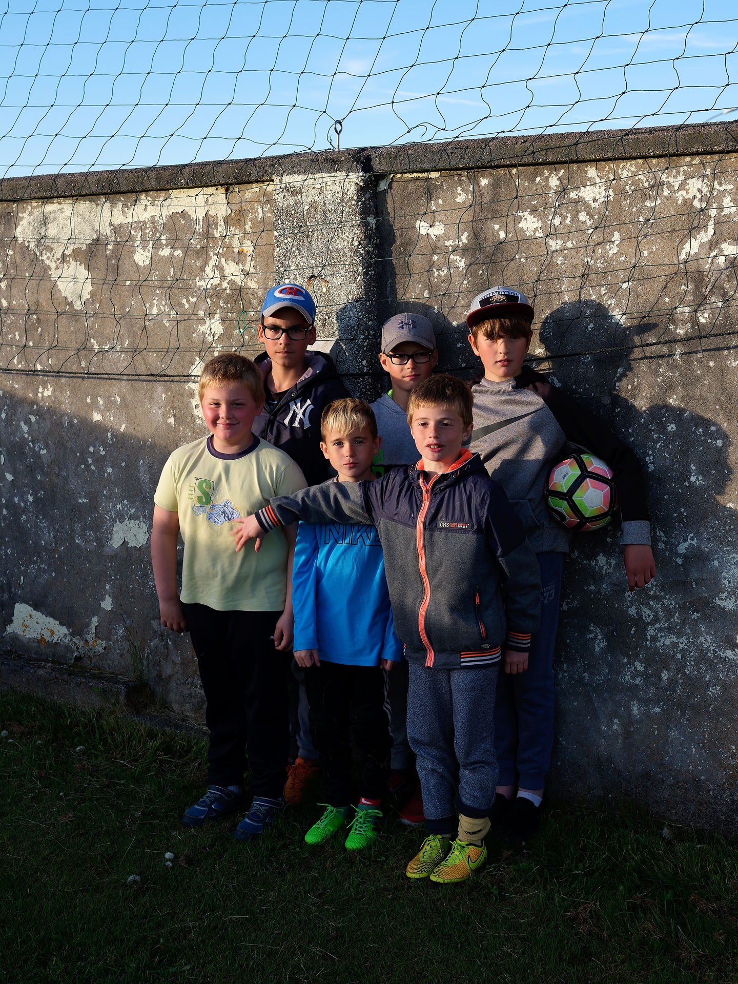 group of young kids posing against a wall with soccer ball by Guillaume Simoneau in Saint-Pierre-et-Miquelon for M le mag Le Monde