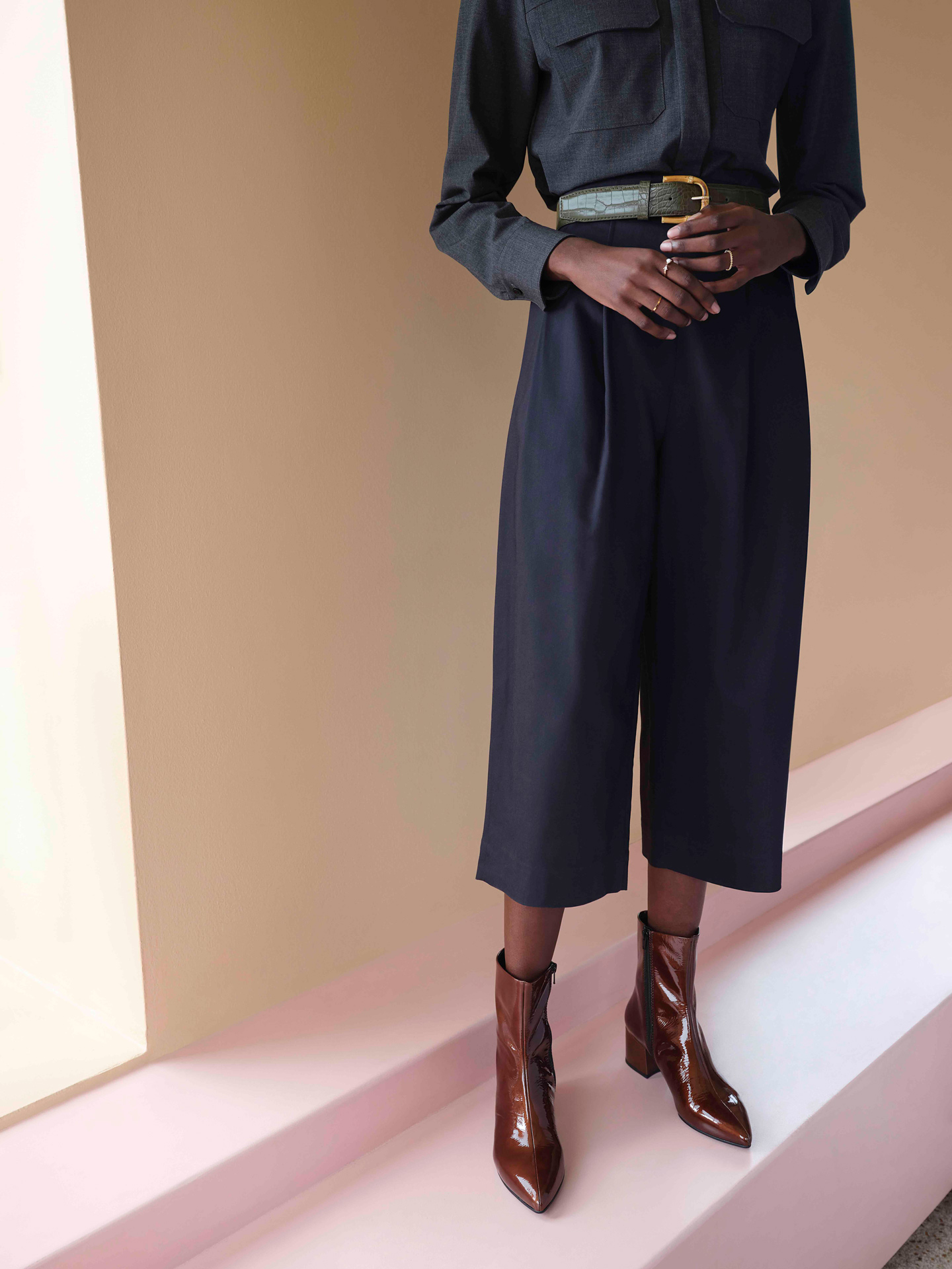 black model wearing large dark blue pants with dark blue shirt and shiny brown high-heeled boots posing on pink ground by Maxyme G Delisle with artistic direction from Studio TB at Pastel Rita for Jean-Paul Fortin Fall collection