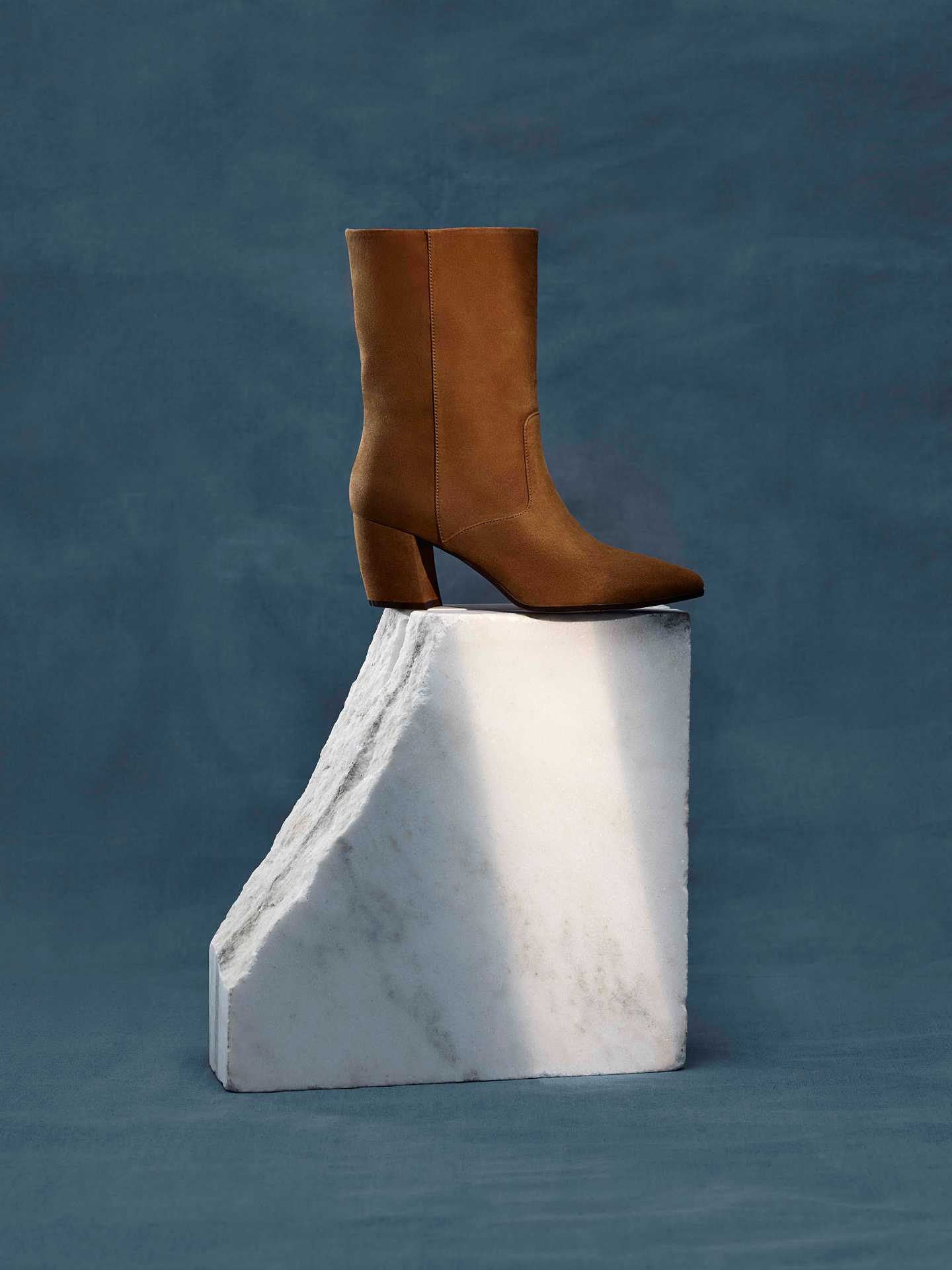 brown suede boot on piece of white marble on blue background by Maxyme G Delisle with artistic direction from Studio TB for Jean-Paul Fortin Fall collection