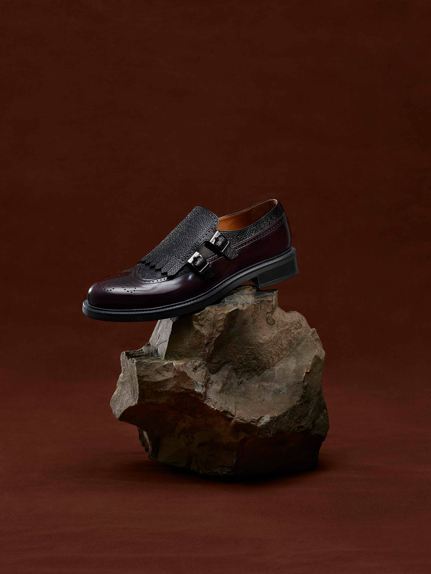 black leather shoe on brown rock on dark red background photographed by Maxyme G Delisle with artistic direction from Studio TB for Jean-Paul Fortin Fall collection
