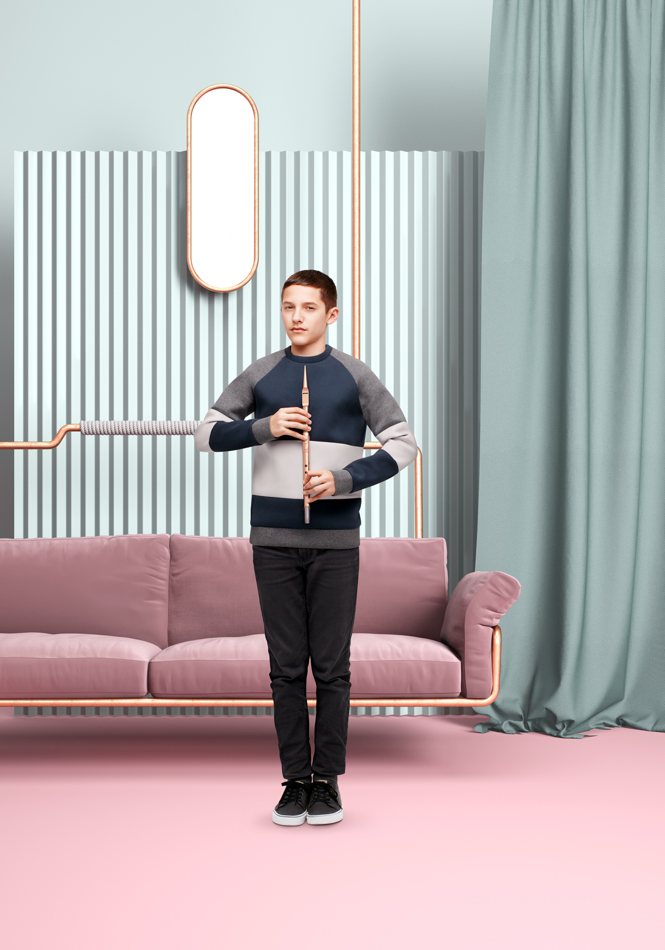 young boy holding flute with two hands looking at camera in front of pink couch held by copper pipes textured background and dark turquoise drapes by Simon Duhamel for Bloom Maestro