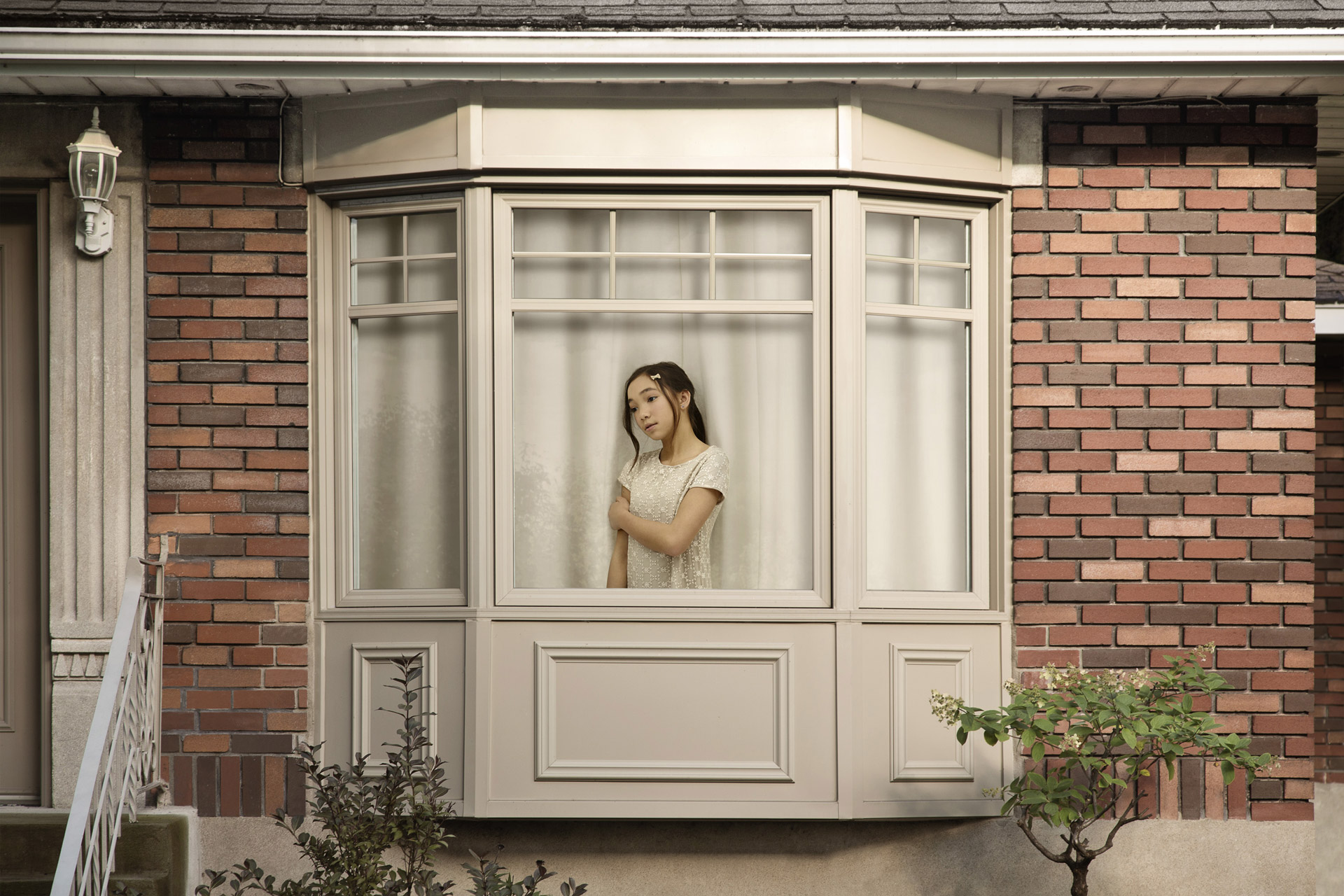 young asian girl dressed in white inside house looking sadly out the window by Simon Duhamel for In Between
