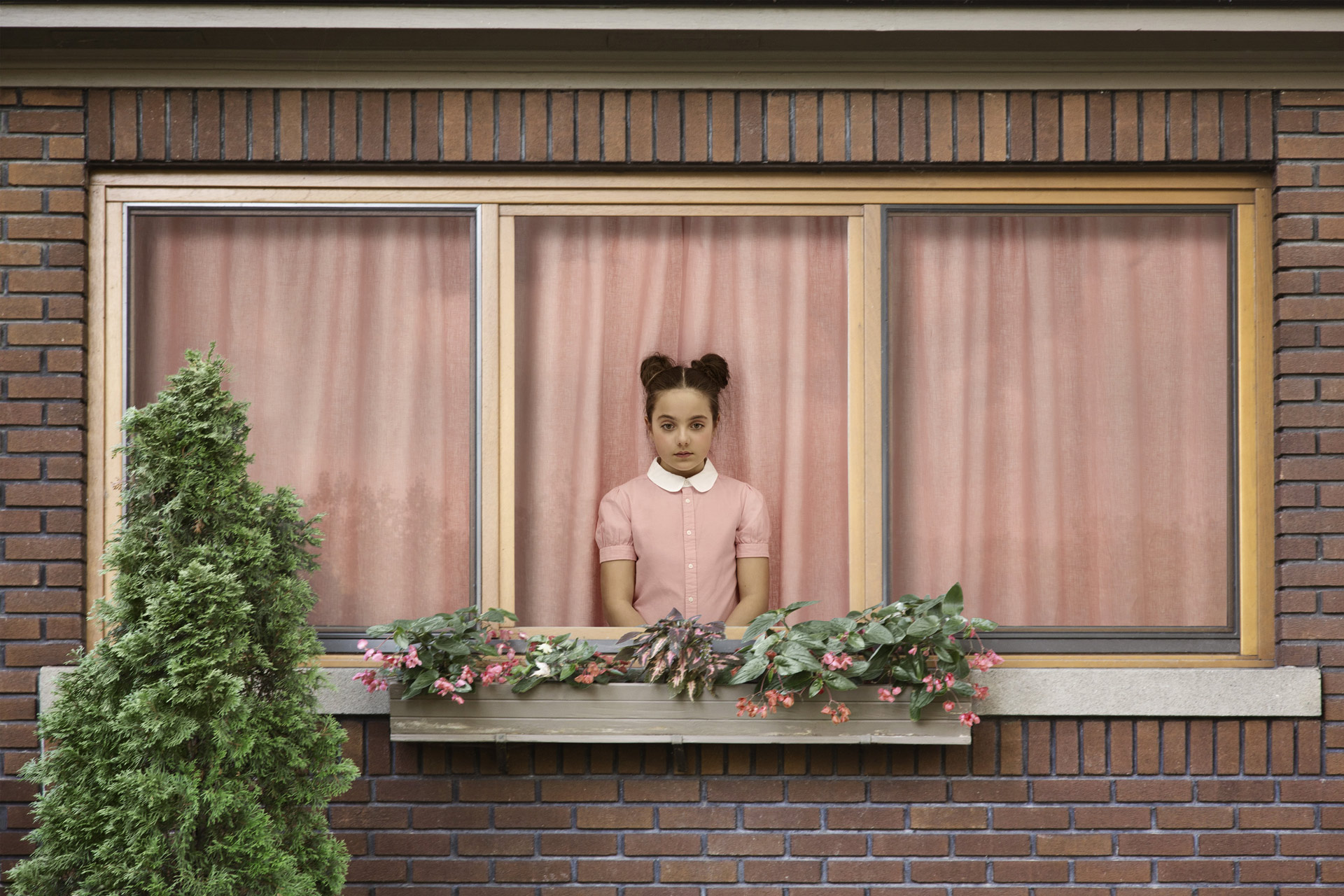 young girl dressed in pink inside house looking sadly out the window by Simon Duhamel for In Between
