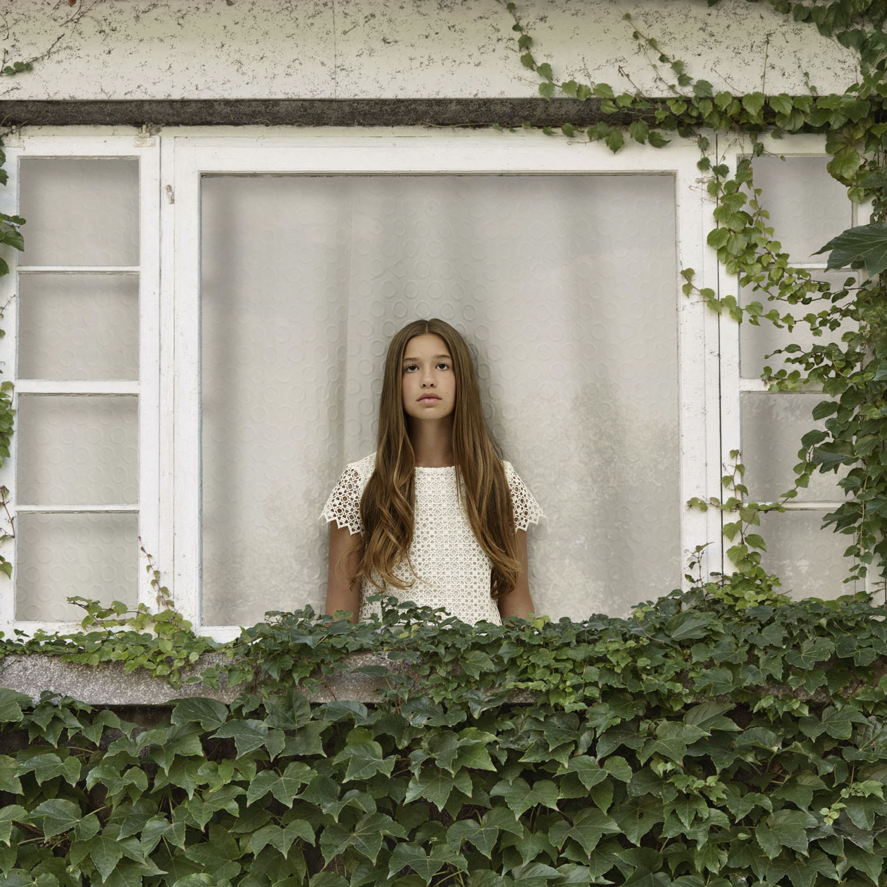 young brown haired girl dressed in white inside vine covered house looking sadly out the window by Simon Duhamel for In Between