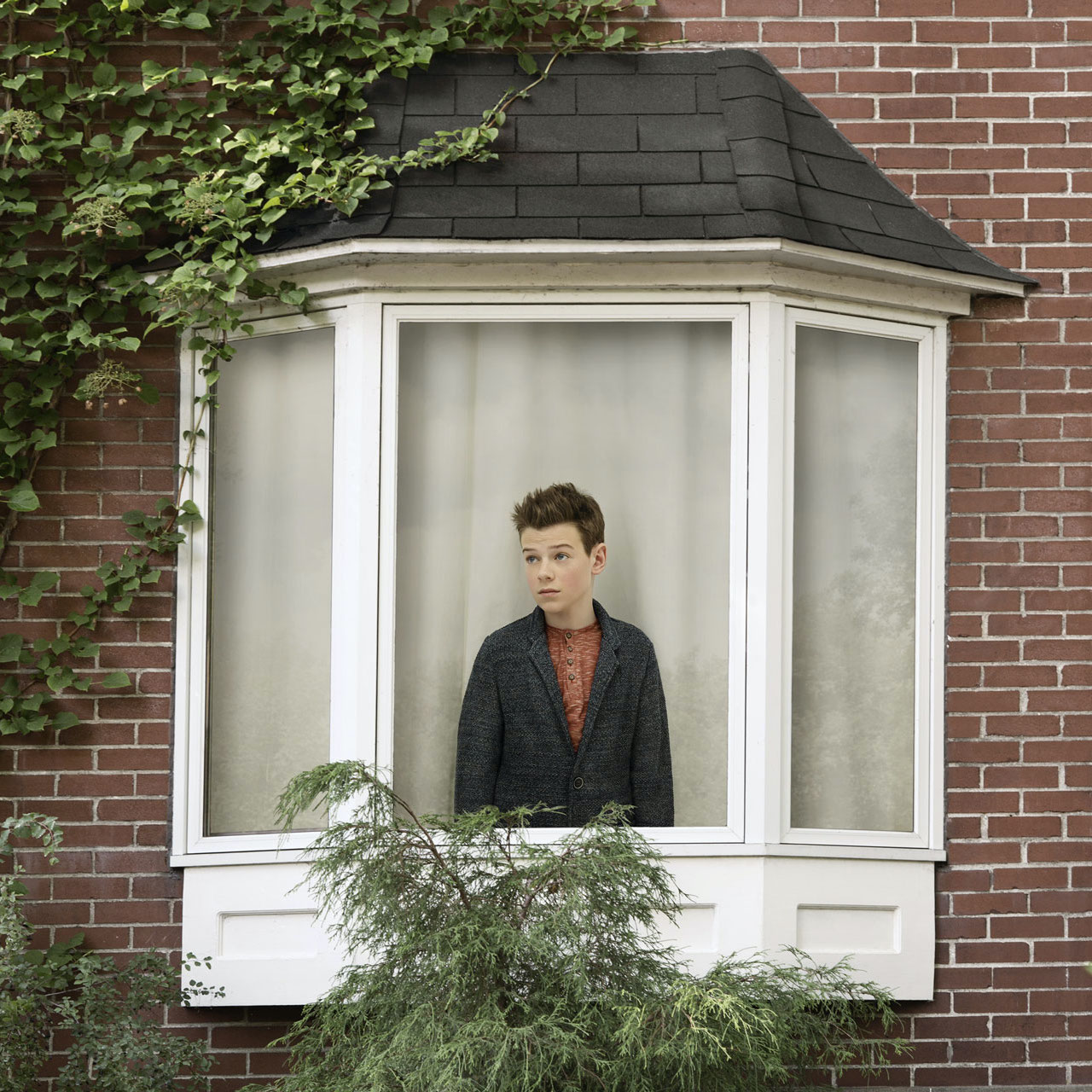 young boy inside house looking out the window by Simon Duhamel for In Between