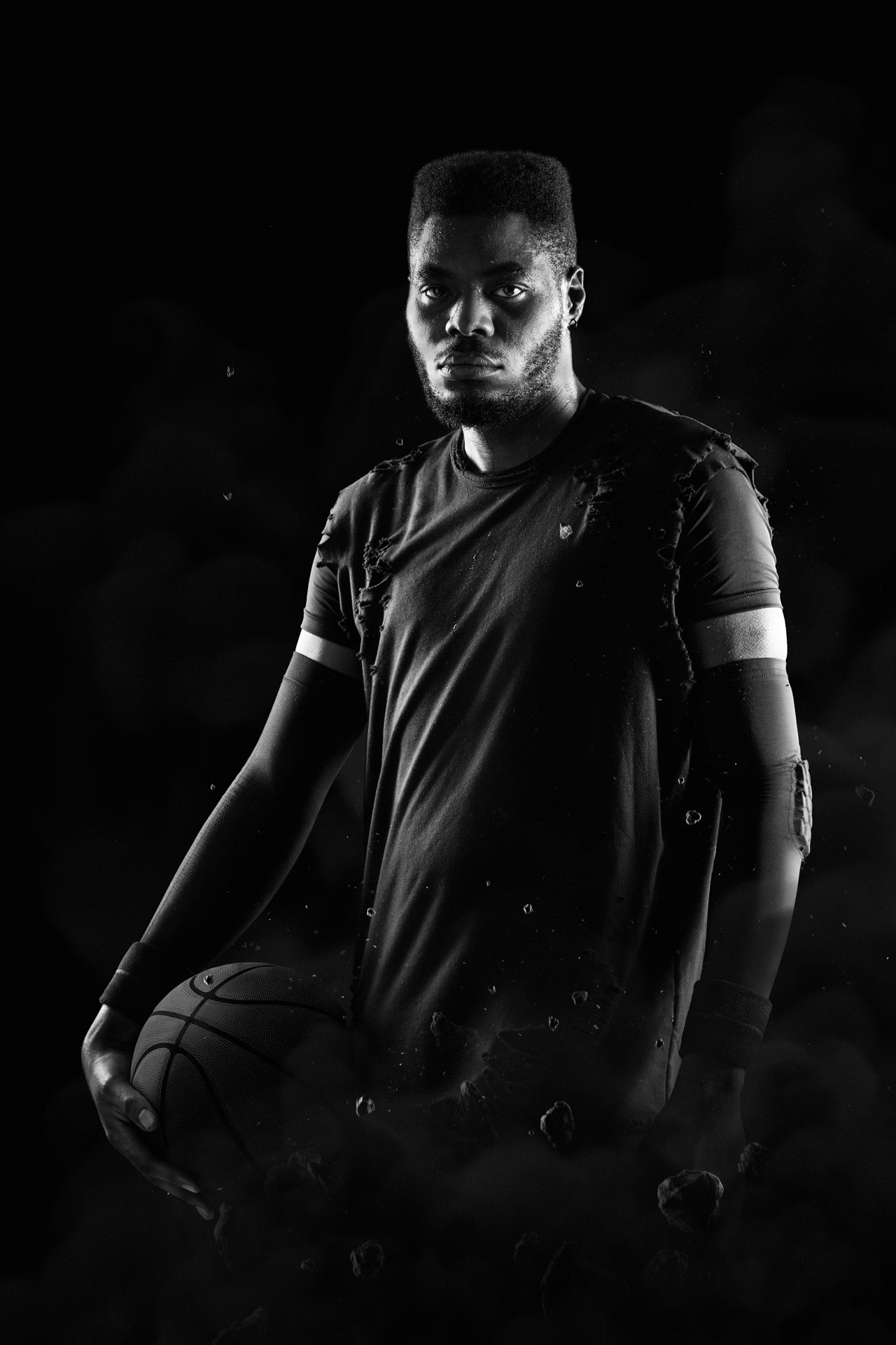 black man posing as basketball player looking at camera holding basket ball low lighting black and white by Simon Duhamel for W-Hoop