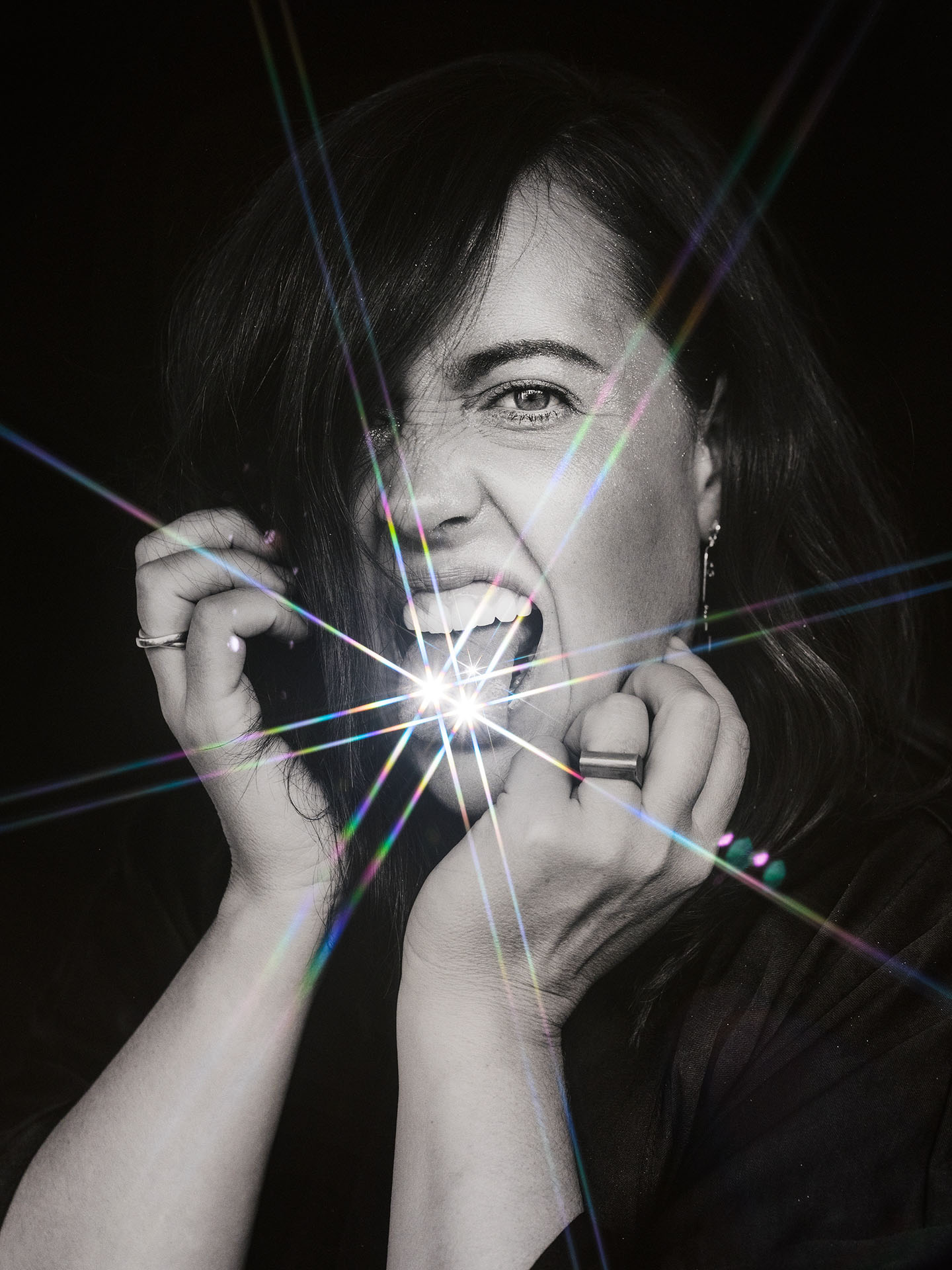 portrait of Ariane Moffatt in black and white sticking tongue out bling on tongue on black background by Jocelyn Michel for Voir