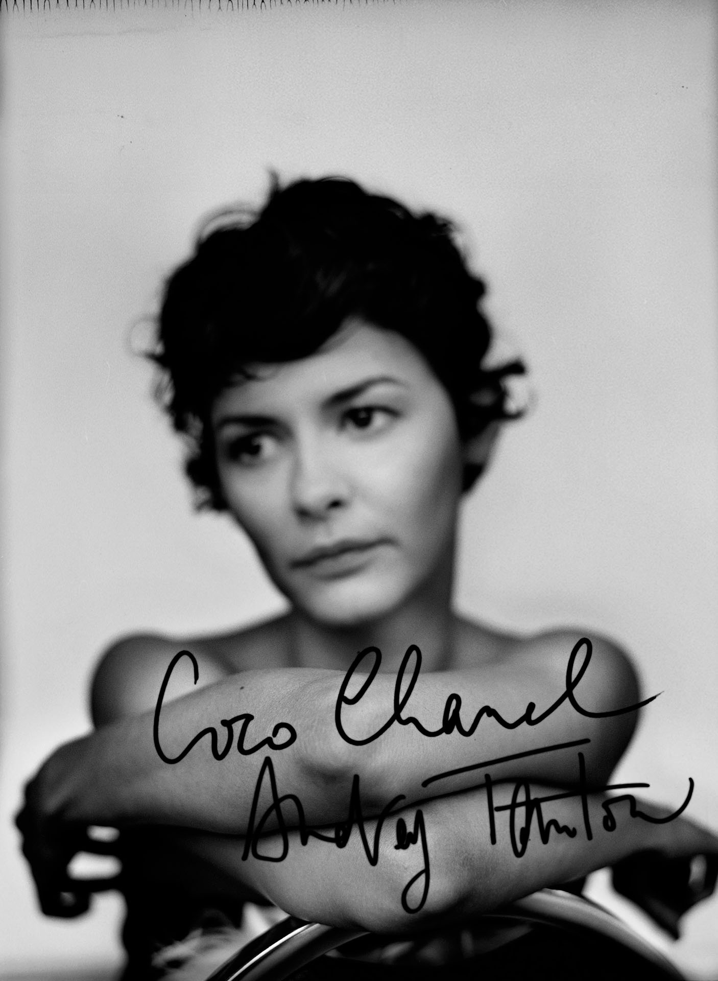blurred portrait of Audrey Tautou in black and white sitting backward on chair on white background white autograph of coco chanel in foreground by Jocelyn Michel for Voir