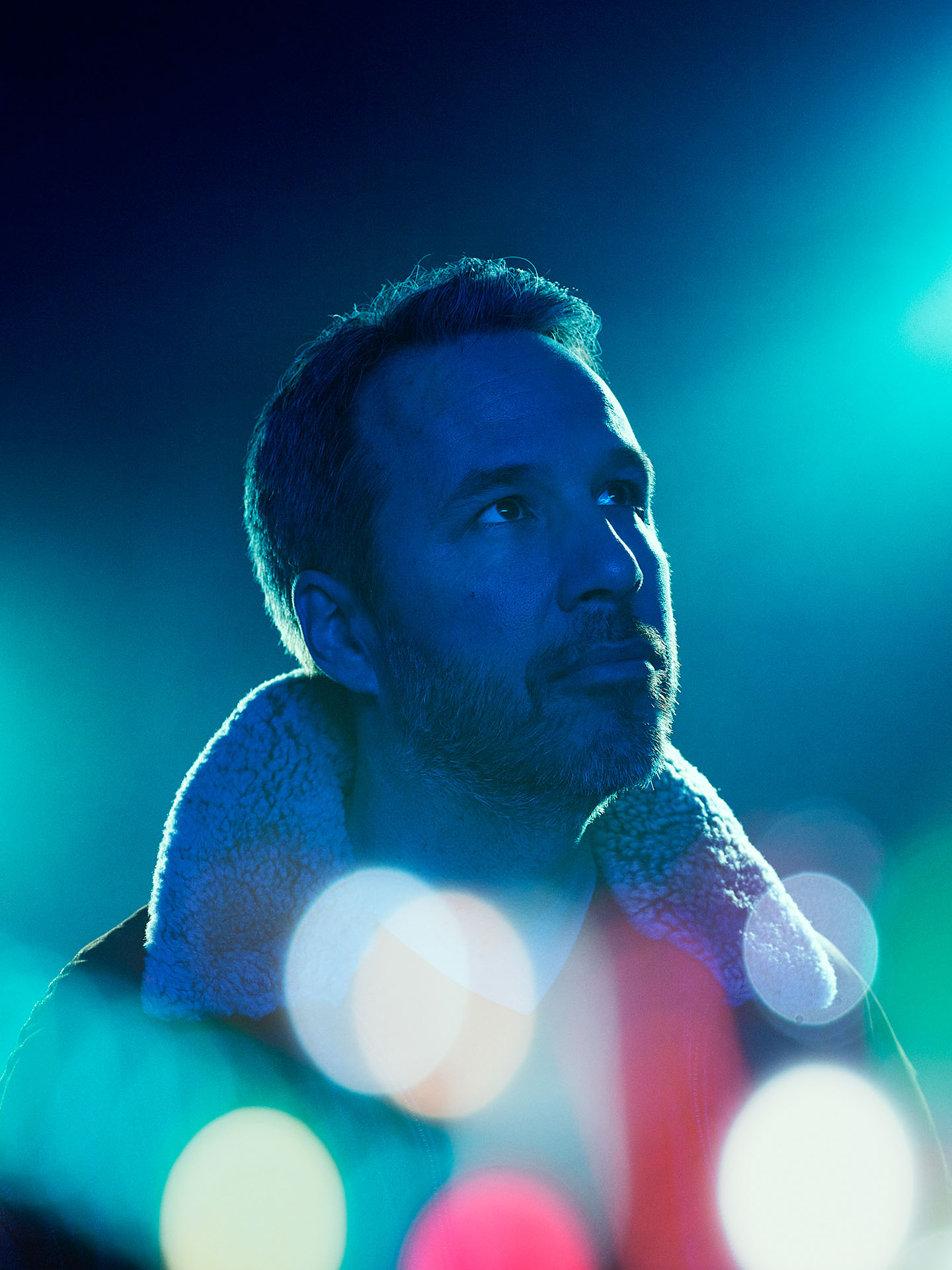 portrait of Denis Villeneuve in blue lighting on blue background and bokeh effect by Jocelyn Michel for Voir