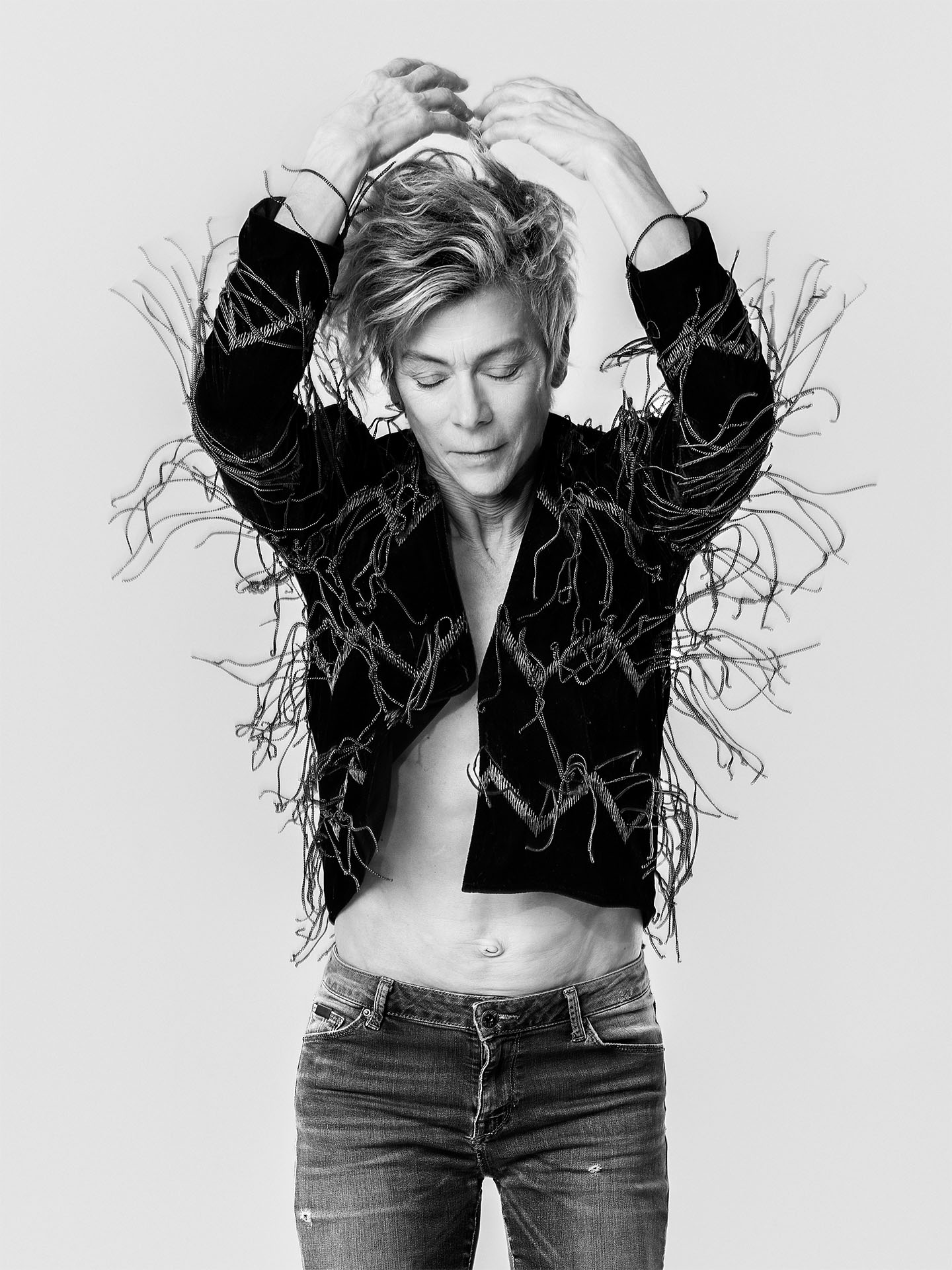 portrait black and white of Louise Lecavalier jumping up wearing fringed vest eyes closed by Jocelyn Michel for Voir