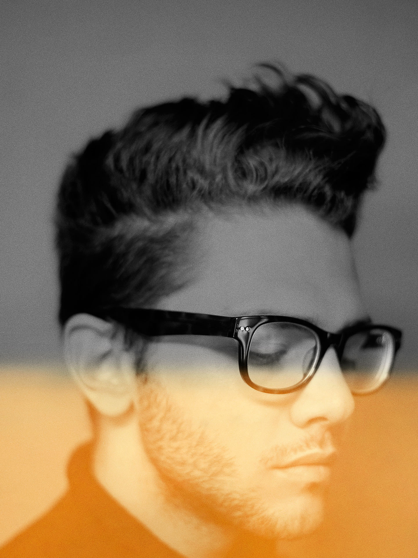 black and white portrait of Xavier Dolan blurred around the edges with orange effect on image by Jocelyn Michel for Voir