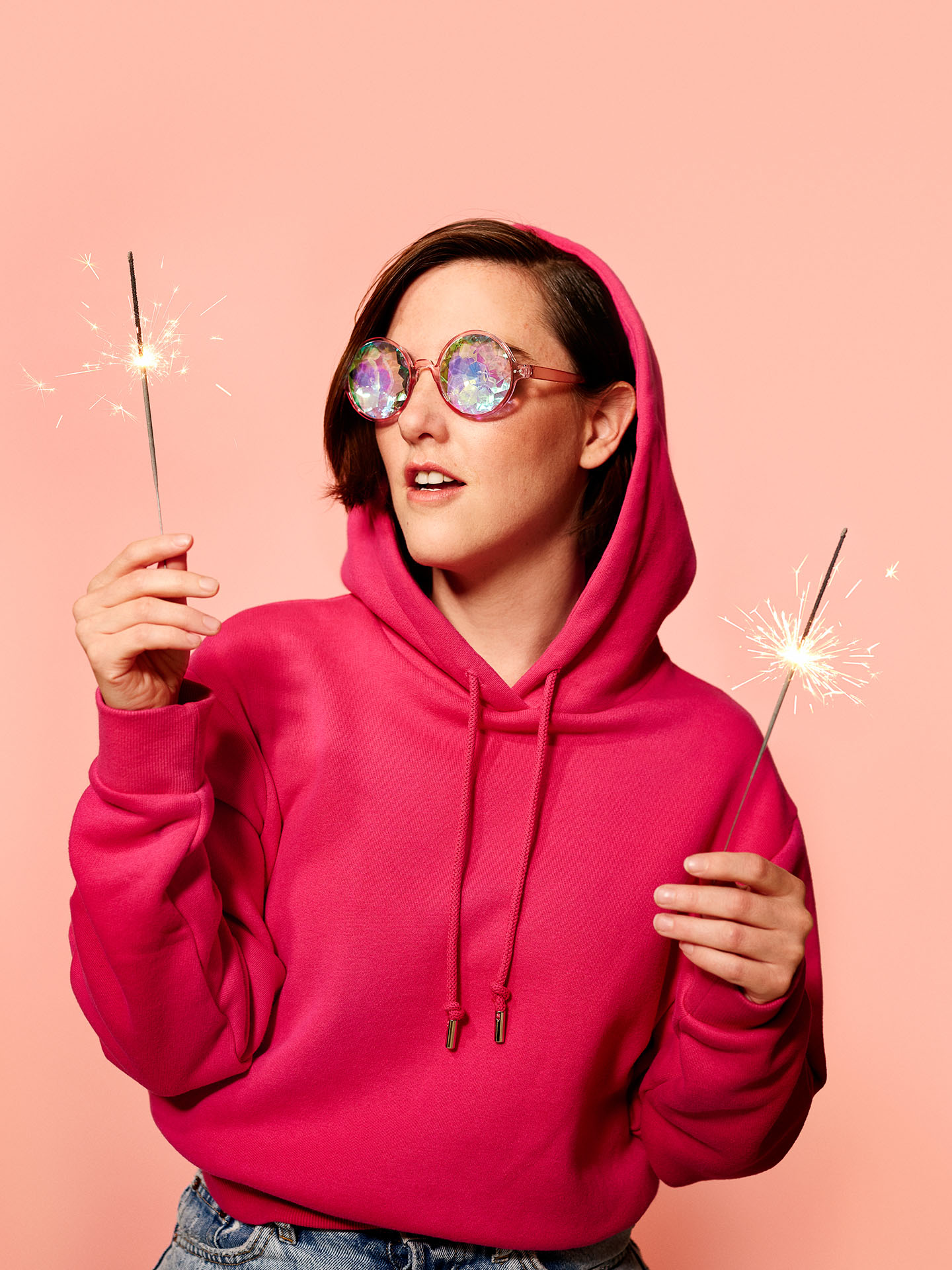 portrait of Florence Longpre wearing bright pink hoodie holding candle sticks on light pink background by Jocelyn Michel for Voir