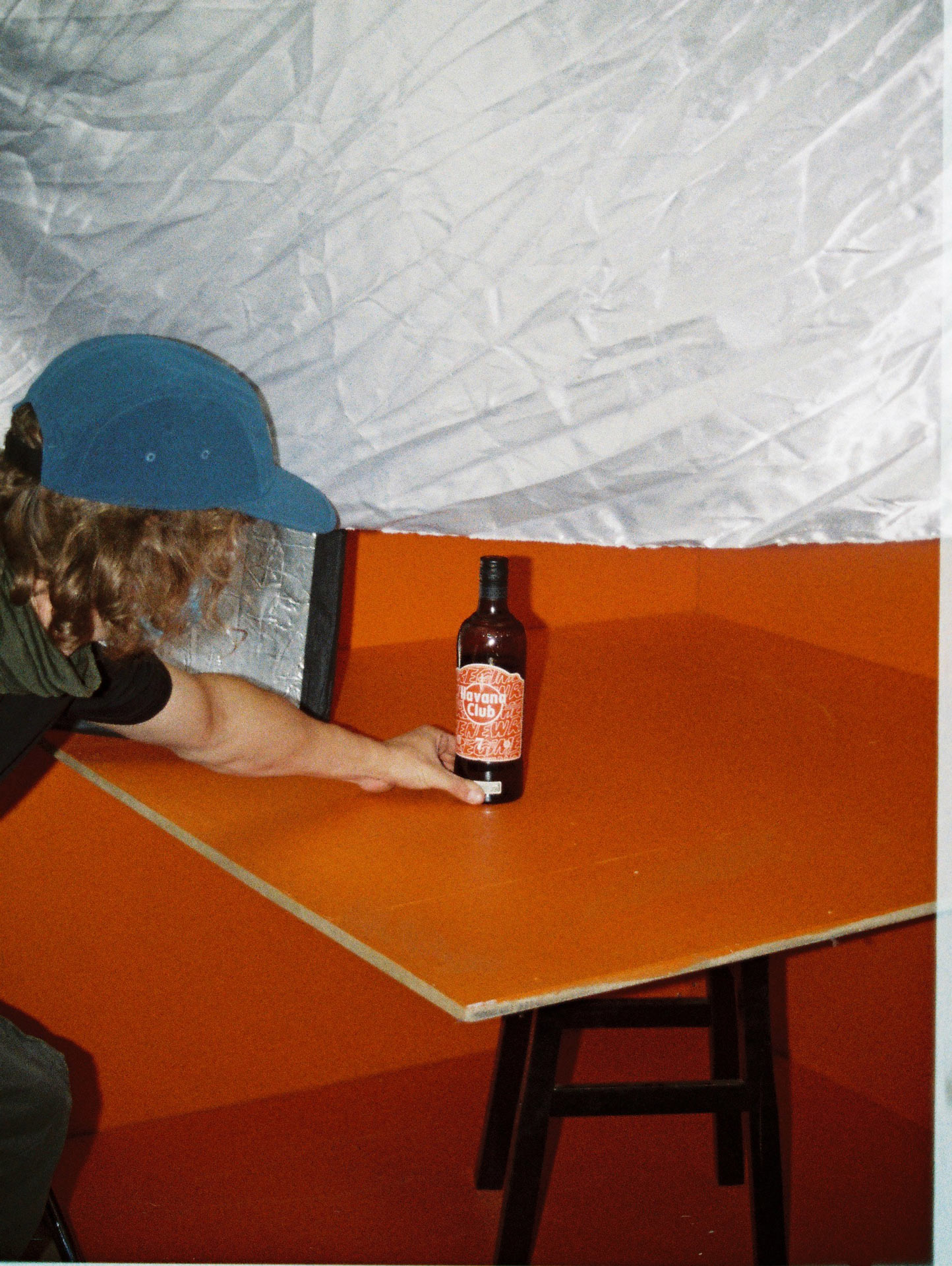 Vincent Ruel-Cote placing bottle of Havana Club brown rhum on orange background for video portrait filmed by Les Gamins for collaboration between Atelier New Regime and Havana Club