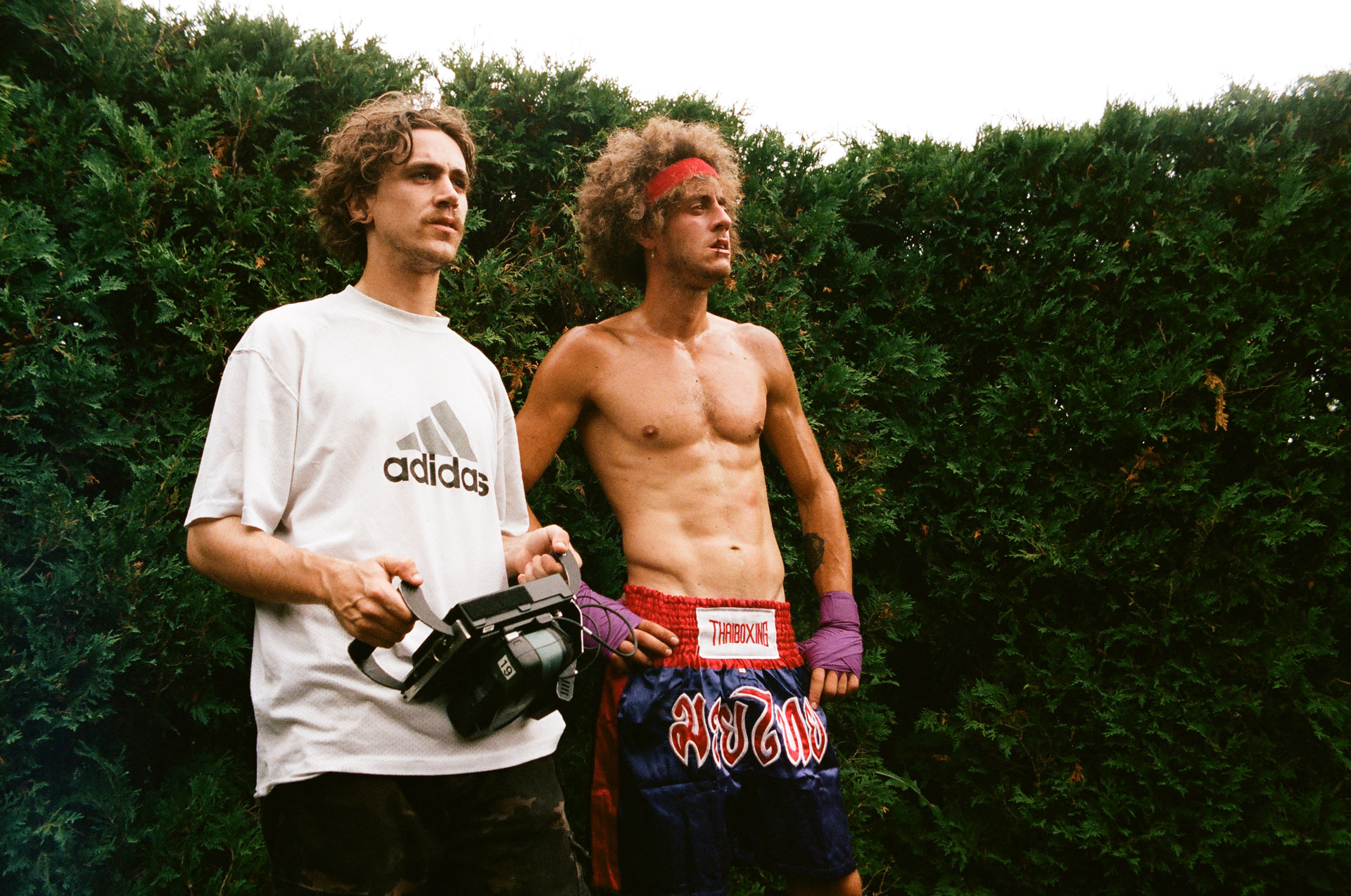 Vincent Ruel-Cote from Les Gamins holding camera next to actor dressed as boxer looking beaten up for Alaclair Ensemble hip hop collective music video Felix